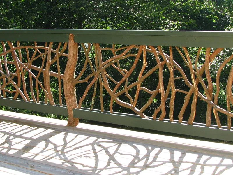 A green painted handrail featuring Mountain Laurel branches and posts, designed to enhance safety and aesthetic appeal on an outdoor patio deck.