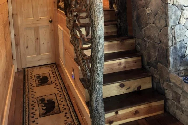 A locust log stair railing featuring bark on full branch posts, designed to enhance safety and add rustic charm to staircases.