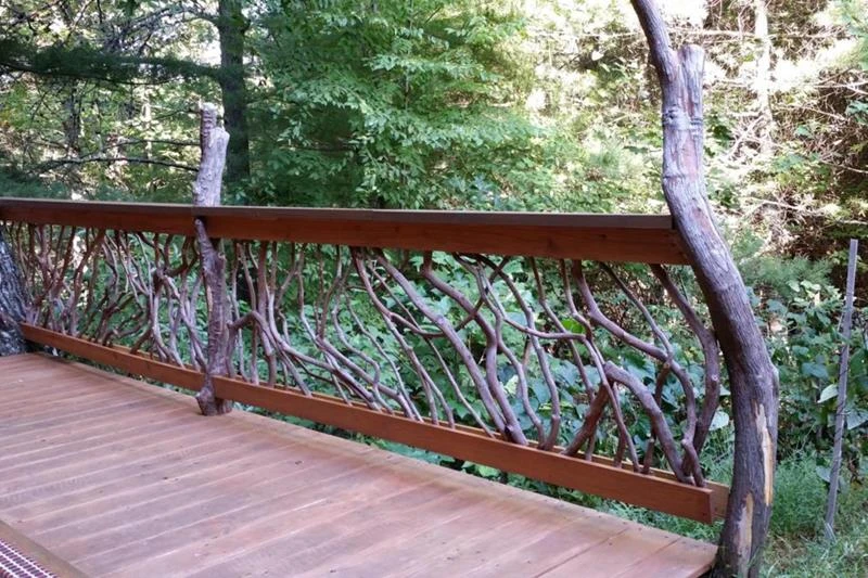 A hot tub deck featuring Mountain Laurel handrails and rustic branch newel posts, designed to enhance safety and aesthetic appeal in outdoor living spaces.