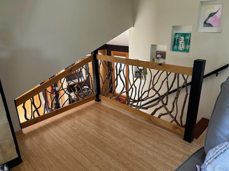 Upstairs reading nook with bamboo flooring and decorative branch-style wooden railing overlooking a staircase.