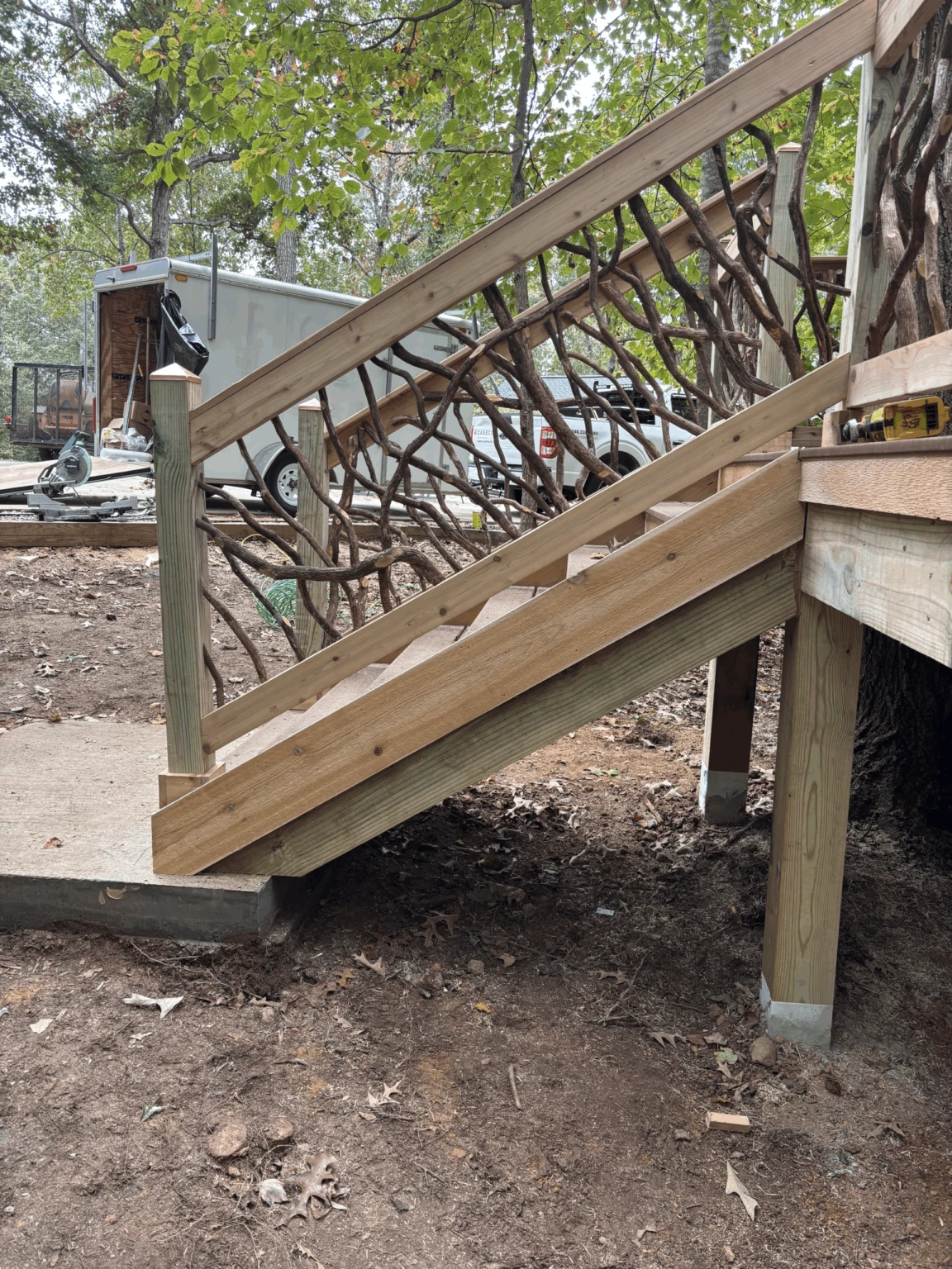 Deck Stairs with Natural Branch Detail Elevated deck stairs with decorative woven branch handrails in a forest setting.