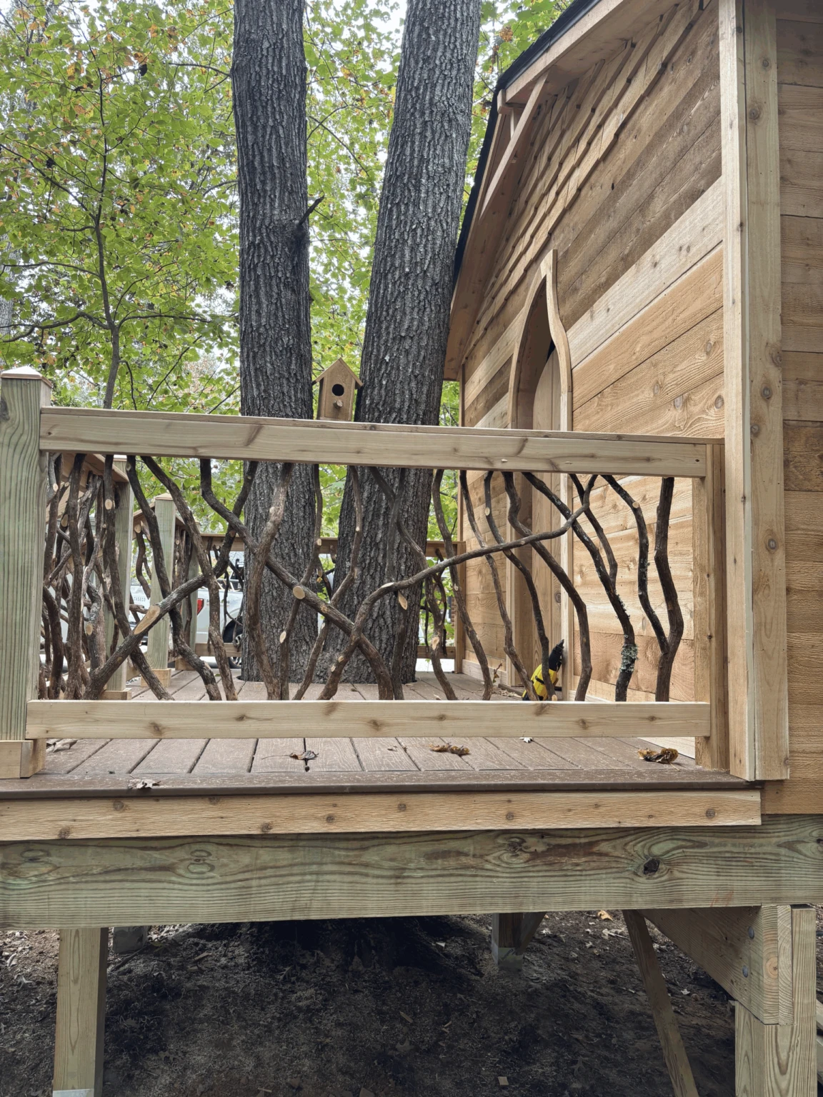 Woodland Deck with Branch Accents Wooden platform with decorative woven branch railing next to a cabin wall.
