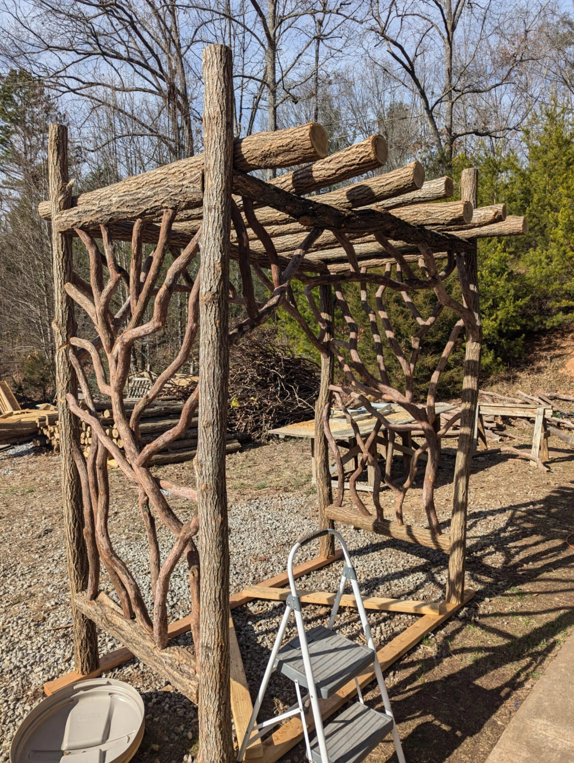 Wooden outdoor structure with branch panels and log beams.