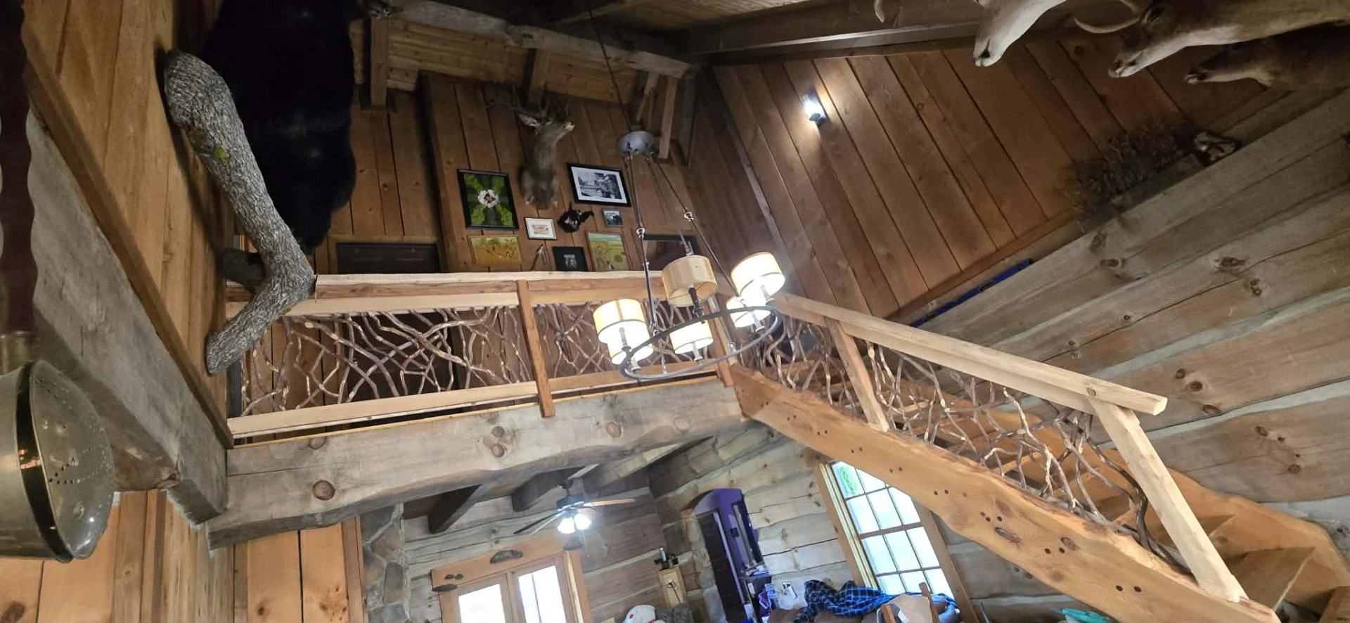Log cabin loft with wooden railing and woven branches, surrounded by taxidermy.