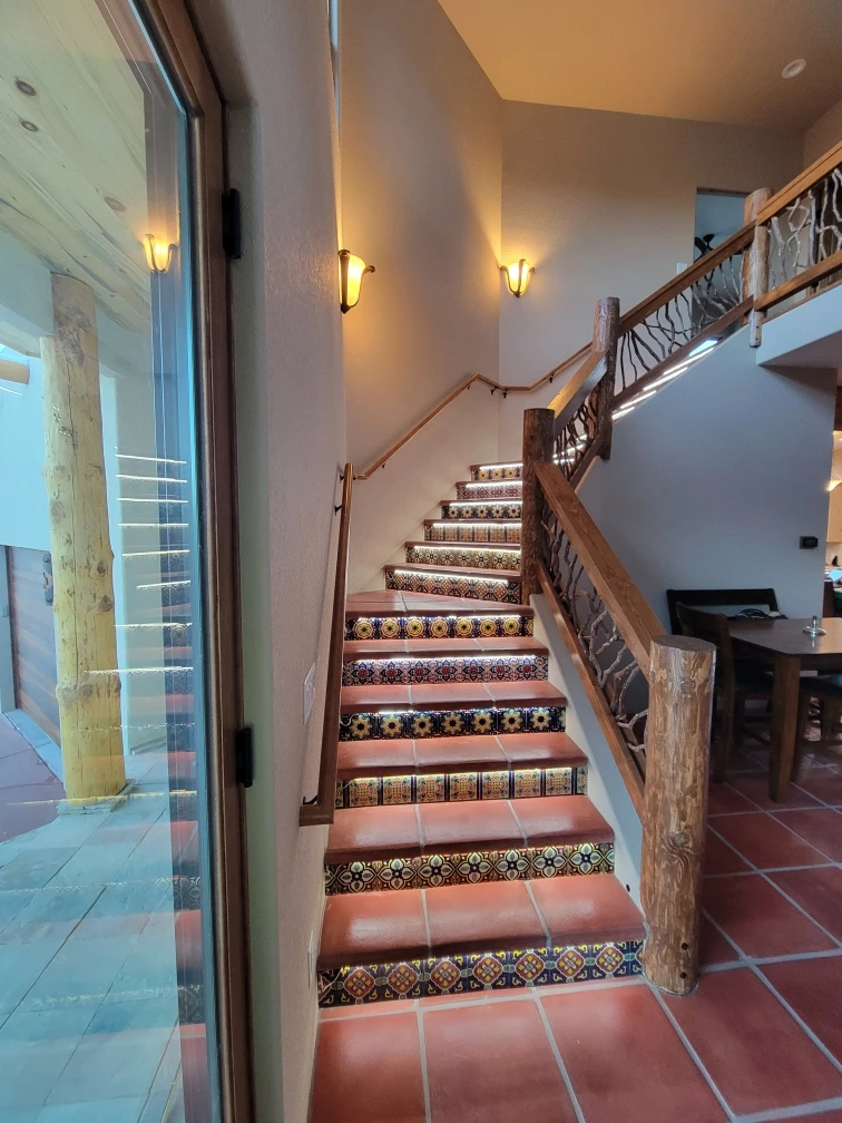 Decorative tiled staircase with wooden handrail in a warm interior setting